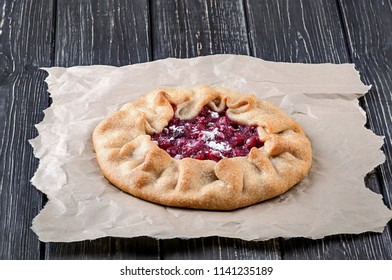 Open Pie Galette With Red Gooseberry On Crumpled Paper And Wooden Table