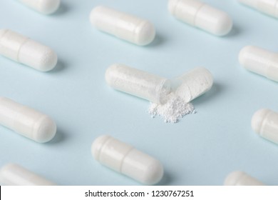 Open pill capsuble with white powder substance macro among closed medicine pattern