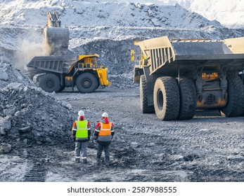 Open pit coal mining with two male workers in high visibility gear, aerial top view.