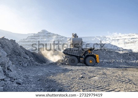 Open pit coal mining in winter: excavator and dump truck operations in snowy landscape.