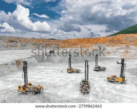 Open pit drilling rigs on limestone quarry with dramatic clouds for mining site. Concept background and industrial extraction of copper, gold ore.