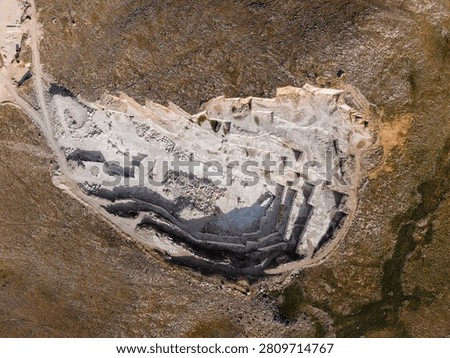 Open pit Marble quarry with stepped benches in rocky landscape.