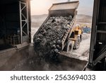 Open pit mine, big mining truck unloads ore for crusher. Stones is crushed to recover copper, gold, iron metal.