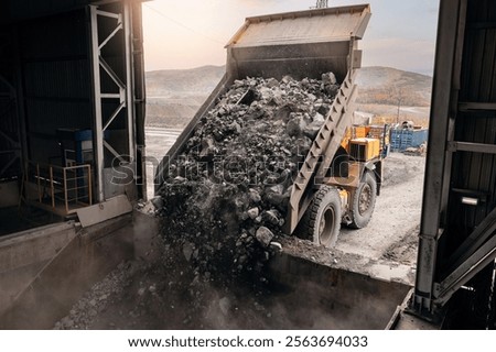 Open pit mine, big mining truck unloads ore for crusher. Stones is crushed to recover copper, gold, iron metal.