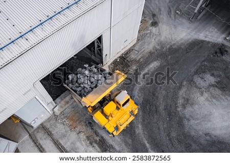 Open pit mine, big mining truck unloads gold ore for crusher, aerial top view.