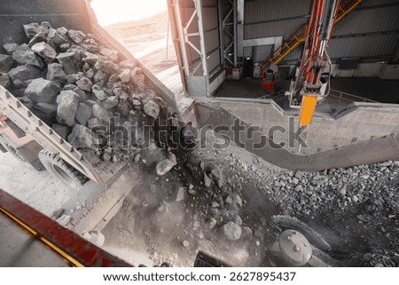 Open pit mine, big mining truck unloads ore for crusher. Stones is crushed to recover copper, gold, iron metal.