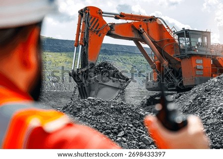 Open pit mine industry, Engineer worker controls process of loading coal into dump truck via radio.