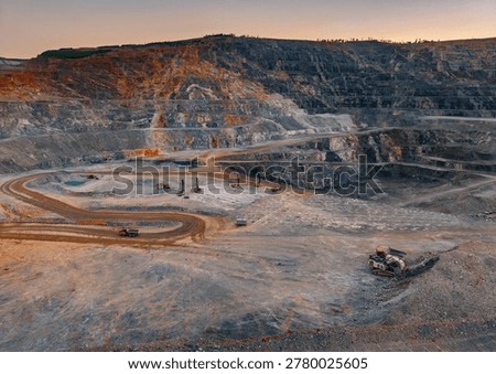 Open pit mine operating with heavy machinery at gold quarry.