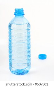 Open Plastic Bottle With Water And Cup Behind