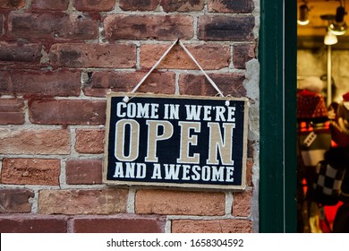 “Come in we’re open and awesome.” A playful sign invites customers into a store.