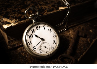 Open pocket watch and a stack of books.