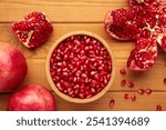 Open pomegranates, and pomegranate seeds on wooden background. Top view