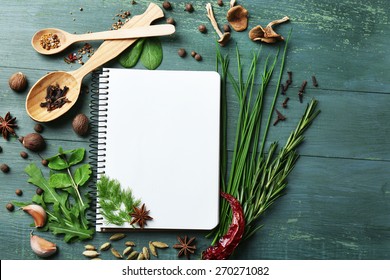 Open recipe book with fresh herbs and spices on wooden background - Shutterstock ID 270271082