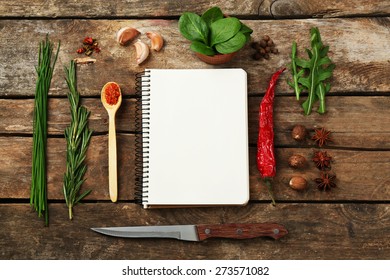 Open recipe book with fresh herbs and spices on wooden background - Shutterstock ID 273571082