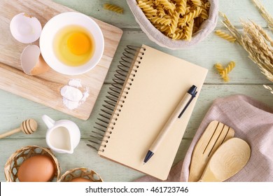 Open Recipe Book On Green Wooden Table With Copy Space, Top View