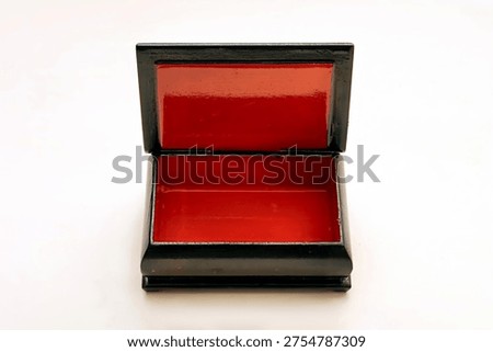 An open, rectangular black box with a striking red interior, placed against a white background, showcasing simplicity and elegance.