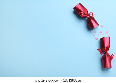 Open Red Christmas Cracker With Shiny Confetti On Light Blue Background, Top View. Space For Text