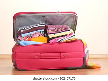 Open Red Suitcase With Clothing In The Room