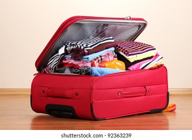 Open Red Suitcase With Clothing In The Room