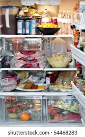 An Open Refrigerator Door Showing A Full Stocked Fridge Loaded Up With Food And Fresh Ingredients.