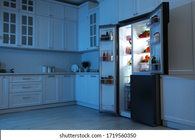 Open Refrigerator Filled With Food In Kitchen At Night