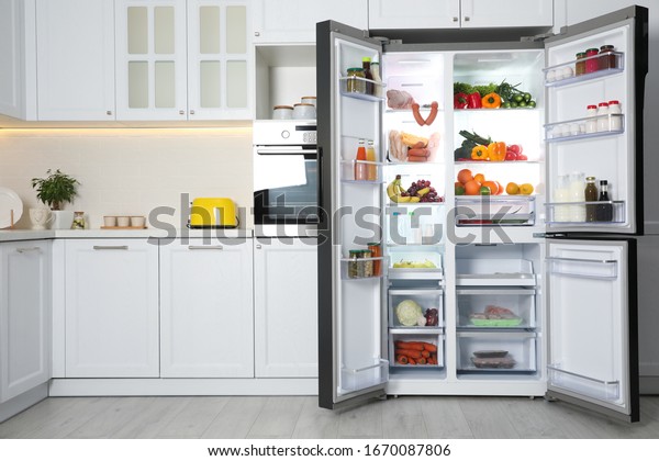 Open\
refrigerator filled with food in\
kitchen