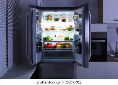 Open Refrigerator Full Of Juice And Fresh Vegetables In Kitchen