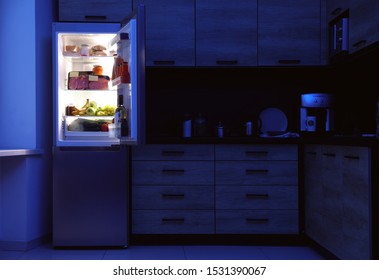 Open Refrigerator Full Of Products In Kitchen At Night