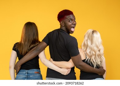 Open Relationship. Casanova Man. Multiracial Love. Date Luck. Lovelace Successful Amazed Happy  Guy Embracing Two Different Women Together Isolated On Orange Background.