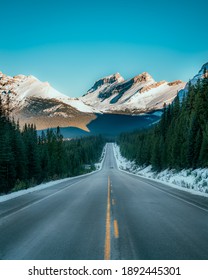 An open road shot in Banff National Park with the Rocky Mountains in the back