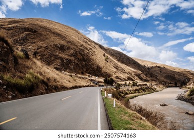 An open road stretches through the vast valley of the Peruvian Andes, with snow-capped mountains towering in the background under a clear blue sky, epitomizing the raw beauty of nature. - Powered by Shutterstock