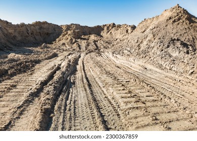 Open sand pit, for sand extraction during construction. The texture of sand and traces of the tread of large cars. Storage of sand at the construction site