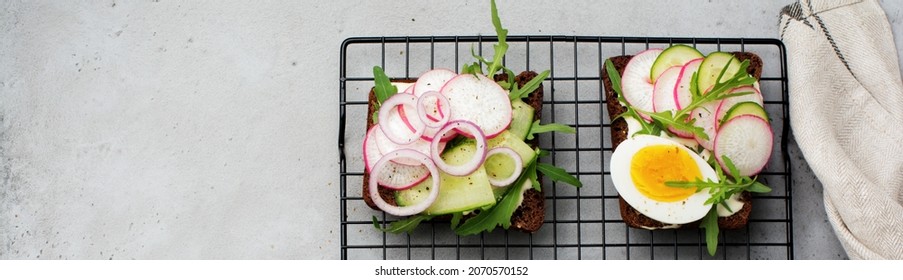 Open sandwiches on dark rye bread with eggs, shrimps, radishes, cucumber, cream cheese and arugula for breakfast. Smorrebrod Traditional dish of Danish cuisine. Top view.