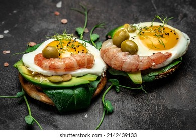 open sanwich with wholemeal bread, soft fried egg, spinach, avocado, shrimps on black background, Ketogenic breakfast. superfood concept. Healthy, clean eating. Top view.