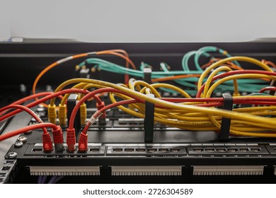 Open server rack with network switches and patch panels, showing disorganised, tangled multi-coloured Ethernet cables