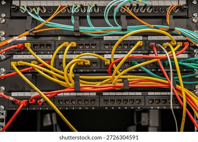 Open server rack with network switches and patch panels, showing disorganised, tangled multi-coloured Ethernet cables