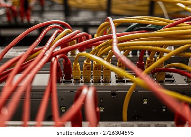 Open server rack with network switches and patch panels, showing disorganised, tangled multi-coloured Ethernet cables