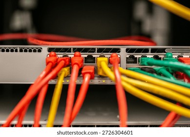 Open server rack with network switches and patch panels, showing disorganised, tangled multi-coloured Ethernet cables