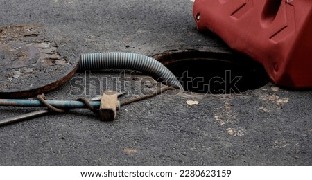 open sewer hatch and inserted a hose for cleaning the septic tank. maintenance of communications in a private house. dirty work