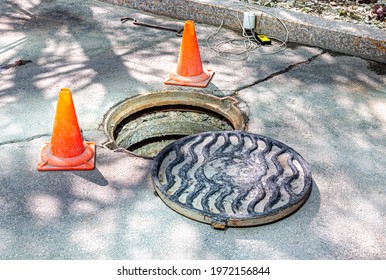 Open sewer manhole on the asphalt road. Accident with sewer hatch in city. Concept of sewage, repair of underground communications