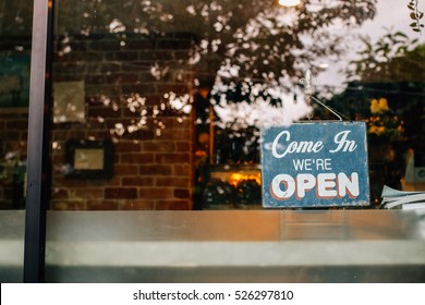 Open Sign Board Close-up Through The Glass Of A Window At Coffee Shop Door. Shallow Depth Of Field.