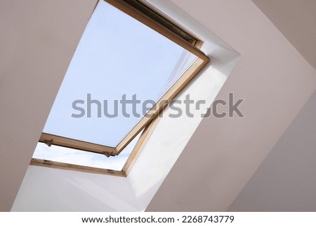 Open skylight roof window on slanted ceiling in attic room