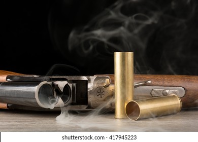Open smoking rifle and two metallic shells. On black background
