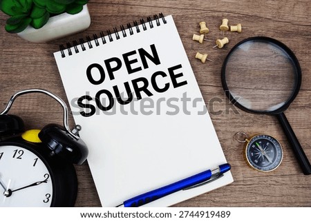 Open Source text written on notepad with alarm clock, compass and magnifying glass flat lay on wooden background