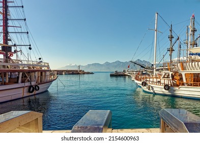 An open space between two ships in the port of Antalya gives a clear view from the pier over turquoise water to the port exit and the Olympos mountain Tahtali rising  on the horizon - Powered by Shutterstock