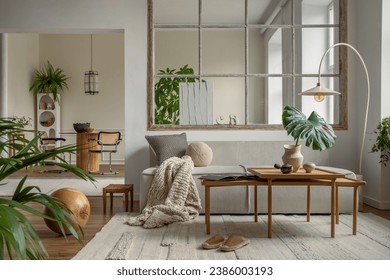 Open space interior with modular sofa, wooden coffee table, big window, beige rug, braided plaid, pillows, round table, lamp, plants, slippers, ball and personal accessories. Home decor. Template.