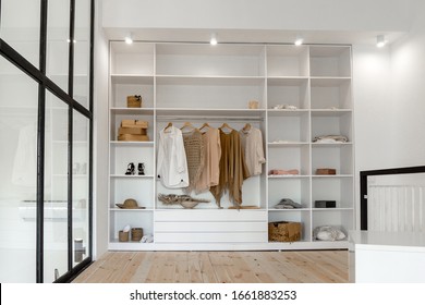 Open space minimalistic scandinavian white wood walk in closet and wardrobe in neutral beige colors