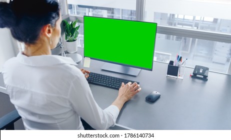 In Open Space Office Businesswoman Working On Her Personal Computer With Green Mock-up Screen. Shot In Big Bright Modern Open Space Office.