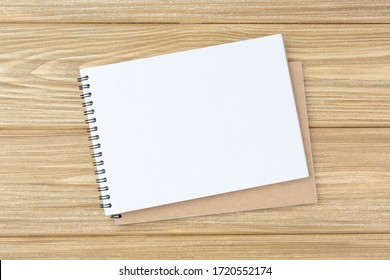 Open spiral notebook on a wooden table. Design concept with copy space for notes. Blank page flat lay. School notepad Top view. Scrapbook for art.