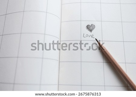 Open squared notebook with pencil drawing heart and handwritten word Love on white paper, concept of education, creativity, romantic message, stationery, study, writing and school supplies